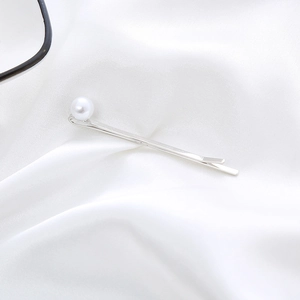 Elegant silver hair clip featuring a white pearl detail on a glossy silk fabric background