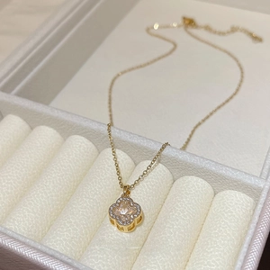 Close-up of gold clover necklace with zircon pendant displayed in a premium jewelry box