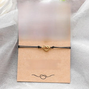 Detail of friendship knot bracelets with gold pendants on a kraft card packaging