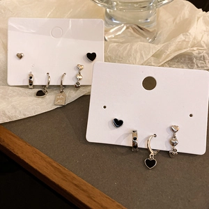 Detail of silver heart earring set featuring black oil drip craftsmanship and heart motifs