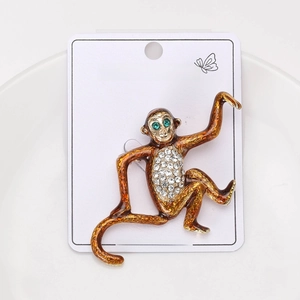 Detailed close-up of brown enamel monkey brooch with sparkling rhinestones on white card