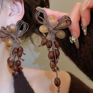 Detail of brown resin bead tassel and woven bow earrings for a vintage aesthetic