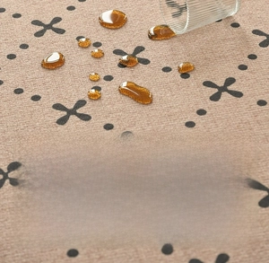 Macro view of waterproof fiber rug showing liquid beading on patterned beige surface
