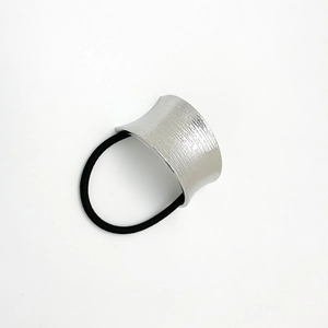 Detail of silver brushed metal U-shaped charm on a black elastic hair tie for women