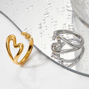 Moderne Herzringe in Gold und Silber mit Hochglanzpolitur auf einer spiegelnden Fläche