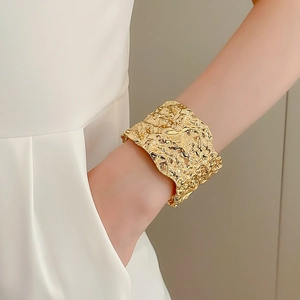 Macro shot of wide gold textured cuff bracelet featuring artistic molten lava style surface