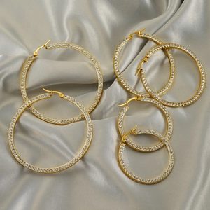 Detailed view of gold plated rhinestone hoop earrings in three sizes on silk background