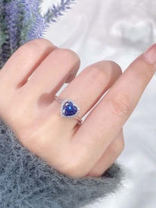 Macro shot of a 925 silver ring featuring a blue heart-shaped gemstone and halo diamonds