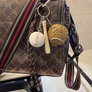 Detailed view of mini baseball keychain with bat and glove hanging on a shoulder bag
