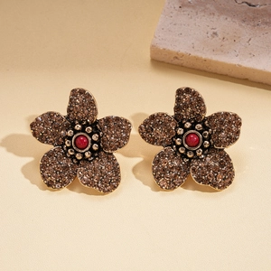 Makroaufnahme von Vintage-Bronze-Ohrsteckern mit braunen Kristallen und roter Perle