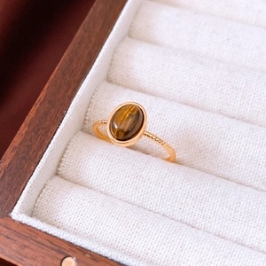 Detailed view of an 18k gold plated tiger eye oval ring in a spiral textured band