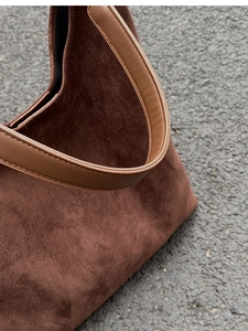 Detail of dark brown suede handbag showing vintage texture and leather handle stitching