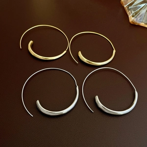 Minimalist geometric gold and silver hoop earrings displayed on premium dark leather background