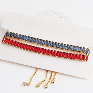 Detail of adjustable gold bracelets with blue and red rectangular cubic zirconia gems