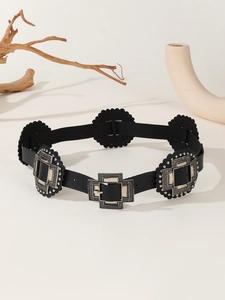 Detail of black leather belt featuring ornate silver buckles and decorative wavy edges