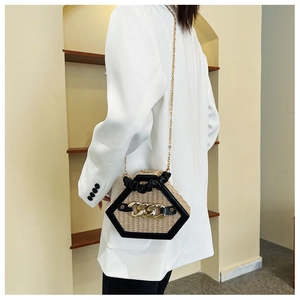 Straw hexagon shoulder bag with black leather trim and gold chain shown on a model