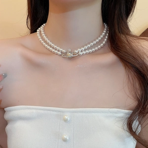 Detail of double-layer pearl choker with Saturn planet pendant on model neck