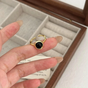 Detail of adjustable gold ring with round black agate stone worn on hand