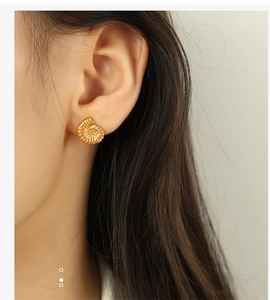 Detail shot of vintage 18K gold plated shell earrings on model showing nautilus texture