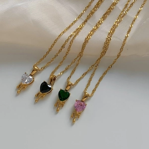 Detail of four heart-shaped zircon necklaces with gold melting metal drip design on silk