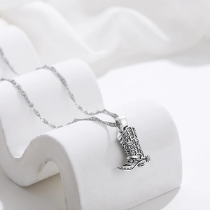 Detailed close-up of silver western cowboy boot pendant with vintage floral engravings