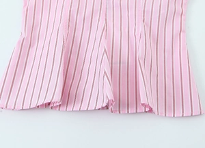 Détail du tissu à rayures verticales roses et blanches avec coutures fines et ourlet volant