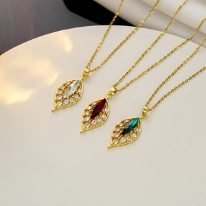 Close-up of three leaf pendants in gold with clear, red, and green marquise zircons
