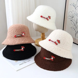 Gros plan sur des bobs en peluche avec écussons lettrés et broderie de champignon