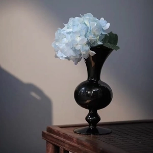 Minimalistische schwarze Glasvase mit blauer Hortensie in einem modernen Kunstambiente