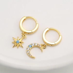Golden earrings with asymmetric star and moon charms featuring blue zircon stones