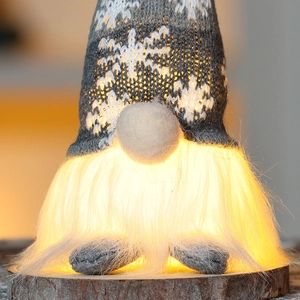 Close-up of a glowing Christmas gnome with knitted snowflake hat and warm LED light details