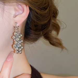 Gros plan d'élégantes boucles d'oreilles grappe en argent portées par un mannequin chic