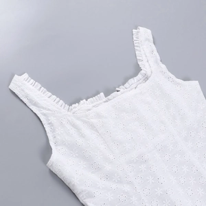 Détail de la broderie florale blanche avec bretelle volantée délicate sur un haut vintage