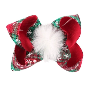 Close-up of red and green plaid Christmas bow with white snowflake prints and pom-pom