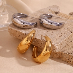 Detailed close-up of polished gold and silver crescent earrings on a stone base