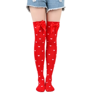 Detail of red over-the-knee socks featuring heart patterns and red bow decorations