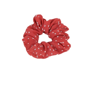 Red fabric hair scrunchie with white polka dot pattern shown in a flat lay view