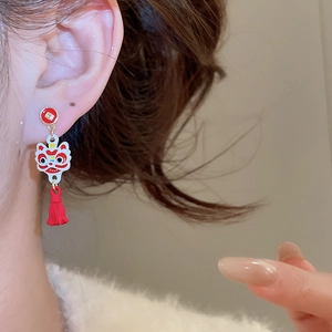 Gros plan sur une boucle d'oreille à gland rouge avec pendentif tête de lion chinois