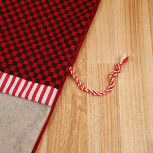 Christmas gift bag with red plaid and striped pattern on warm wood background