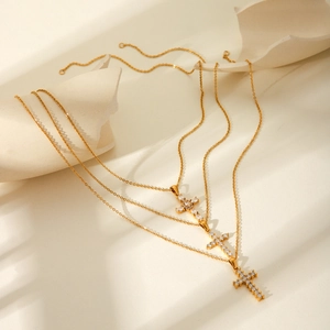 Detailed view of three gold cross pendant necklaces featuring sparkling cubic zirconia stones