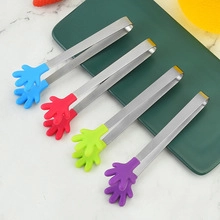 Detail of four palm-shaped silicone food tongs with stainless steel handles on a plate