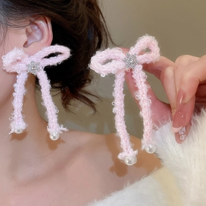 Detailed close-up of pink flocking bow earrings with snowflake charms and pearls