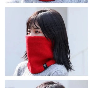 Detail of red cable knit infinity scarf with logo patch worn by female model