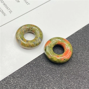 Macro detail of natural unakite stone beads in round donut shape with green and orange texture