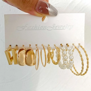 Detail view of 6-pair gold earring set featuring pearls and geometric hoops on card