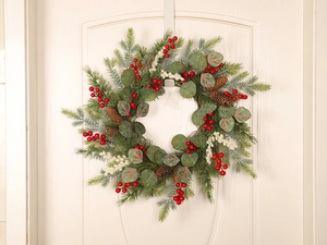 Close-up of Christmas wreath with red berries, eucalyptus leaves and pine cones on a white door