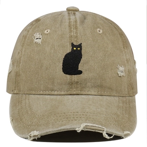 Detail of embroidered black cat patch on vintage distressed khaki cotton baseball cap