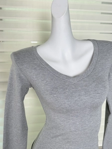 Détail du tissu et des coutures d'un t-shirt gris à manches longues et col en V