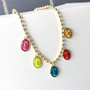 Detail of colorful oval enamel charms and gold beads with religious icons on the necklace