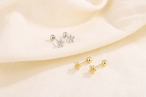 Detail of screw-back mini flower earrings in gold and silver finish with petal design